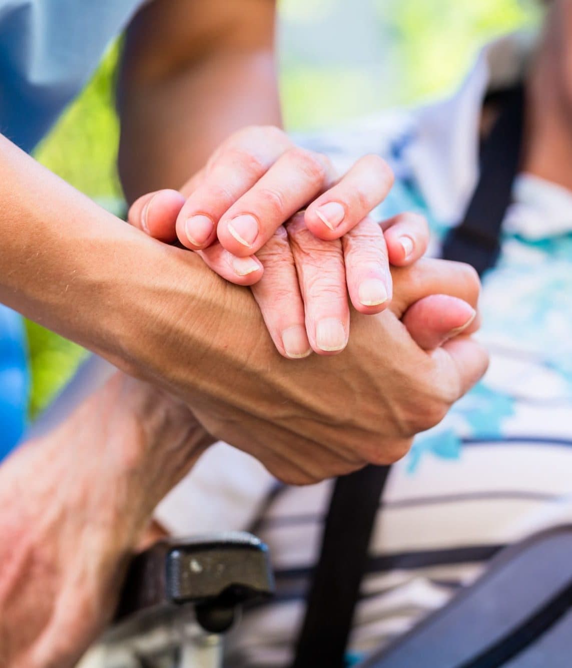 A carer gently holding the hands of an older person