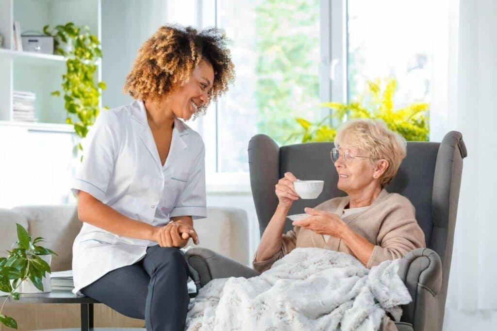 A carer sharing a cup of tea with an older woman in her living room